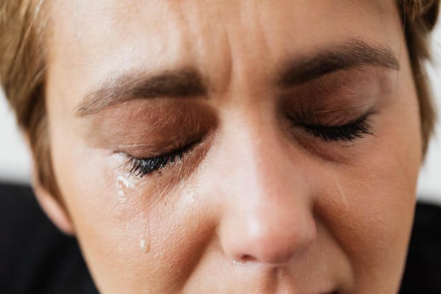 Foto do rosto de uma mulher chorando pelo luto. A foto ilustra o artigo Como curar 10 Estágios do Luto: Lidando com a Perda escrito pelo psicanalista Homero Mônaco para o site Online Psicanalista.