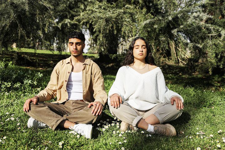 Foto de um casal meditando na natureza para acalmar a turbulência interna. A foto ilustra o artigo Revelando 10 Maneiras Surpreendentes de Lidar com a Turbulência Interna escrito no blog do psicanalista Homero Mônaco para ao site Online Psicanalista.