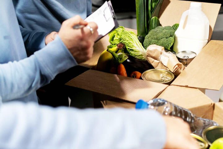 Foto de duas pessoas organizando e anotando alimentos que estão dentro de uma caixa para serem doados em serviço altruísta de voluntariado. A foto ilustra o artigo Revelando 10 Maneiras Surpreendentes de Lidar com a Turbulência Interna escrito no blog do psicanalista Homero Mônaco para ao site Online Psicanalista.