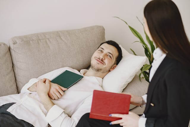 Foto de um homem deitado em um sivâ conversando com sua psicanalista para manter o seu bem-estar emocional. A foto ilustra o artigo 10 Melhores Práticas para Promover o Bem-Estar Emocional escrito pelo psicanalista Homero Mônaco para o site Online Psicanalista.