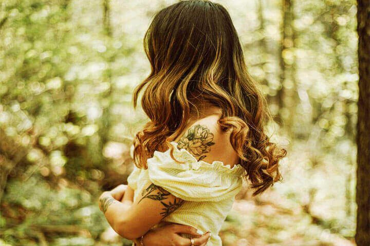 Foto de uma mulher em um parque abraçando a si mesma. A foto ilustra o artigo 10 Passos para Alcançar Equilíbrio Emocional Através da Psicanálise escrito pelo psicanalista Homero Mônaco para o site Online Psicanalista.