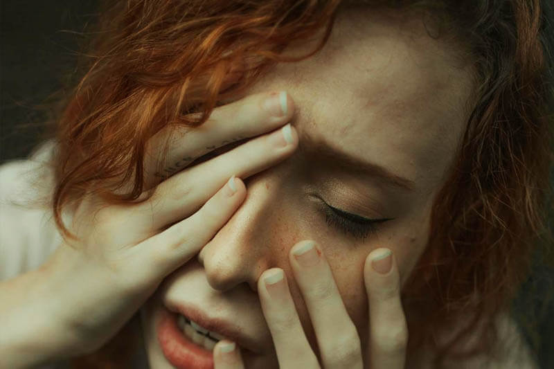 A foto mostra uma mulher ruiva, com as mãoes no rosto e com cara de quem está ansiosa ou tendo um ataque de ansiedade. A foto ilustra o artigo O que é Depressão? Sintomas, Causas e Tratamentos escrito pelo psicanalista Homero Mônaco para o site Online Psicanalista.A foto ilustra o artigo Como controlar a Ansiedade escrito pelo psicanalista Homero Mônaco para o site Online Psicanalista.