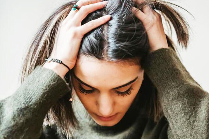 Foto de uma mulher no consultório de seu psicanalista, com as mãos na cabeça como se estivesse com crise de estresse. A foto ilustra o artigo O Papel da Terapia Psicanalítica no combate à Ansiedade, ao Estresse e à Depressão escrito pelo psicanalista Homero Mônaco para o site Online Psicanalista.