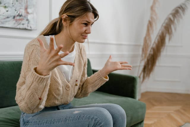 Foto de uma mulher com cabelos castanho claros, sentada em um sofá, parecendo nervosa ao conversar com um psicanalista. A foto ilustra o artigo Como curar Traumas com a Psicanálise escrito pelo psicanalista Homero Mônaco para o site Online Psicanalista.